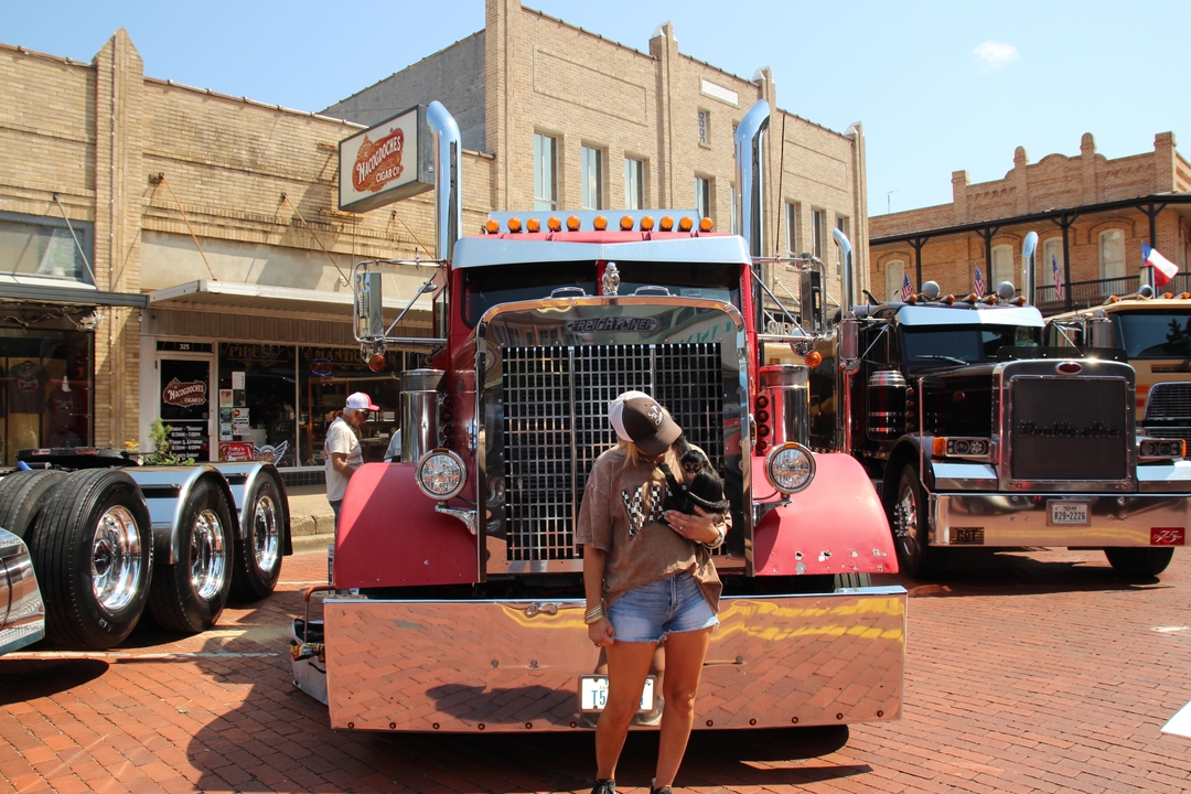 A lady at Old Town Rig Down holding a monkey in front of an 18 wheeler. 